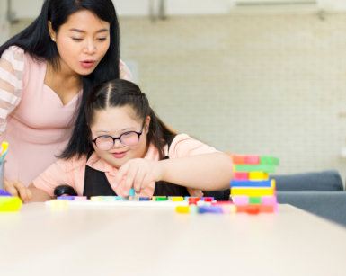 adult woman assisting female kid playing