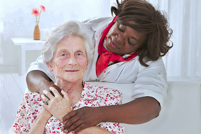 caregiver hugs senior woman smiling