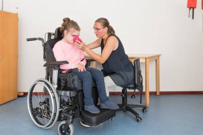 a child in a wheelchair being cared for with the help of a caregiver