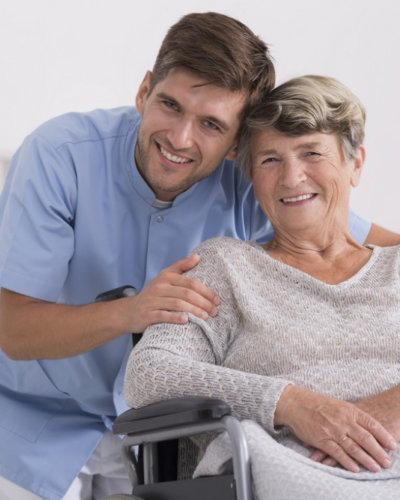 caregiver hugging senior woman sitting in the wheelchair smiling