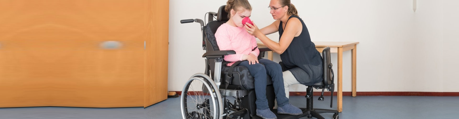 a child in a wheelchair being cared for with the help of a caregiver